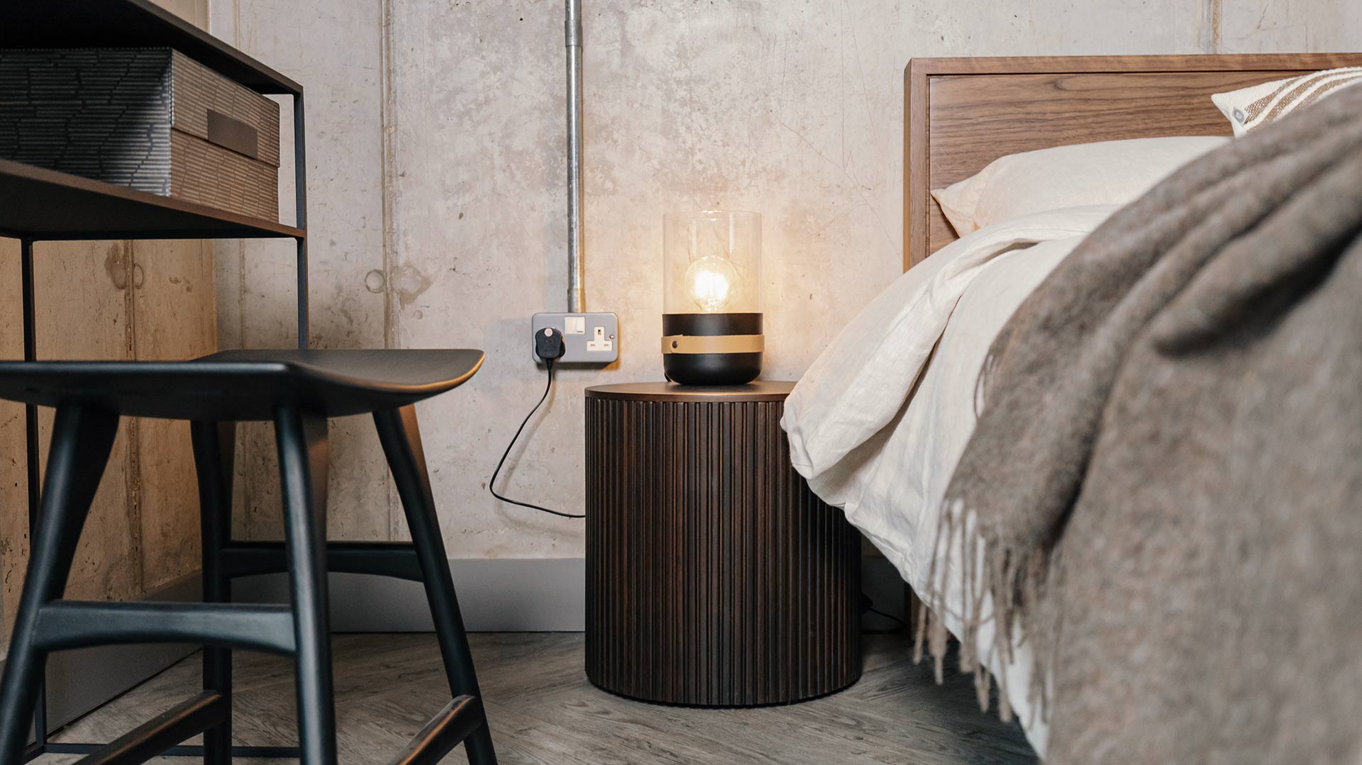 dark wood circular storage table used as bedside table