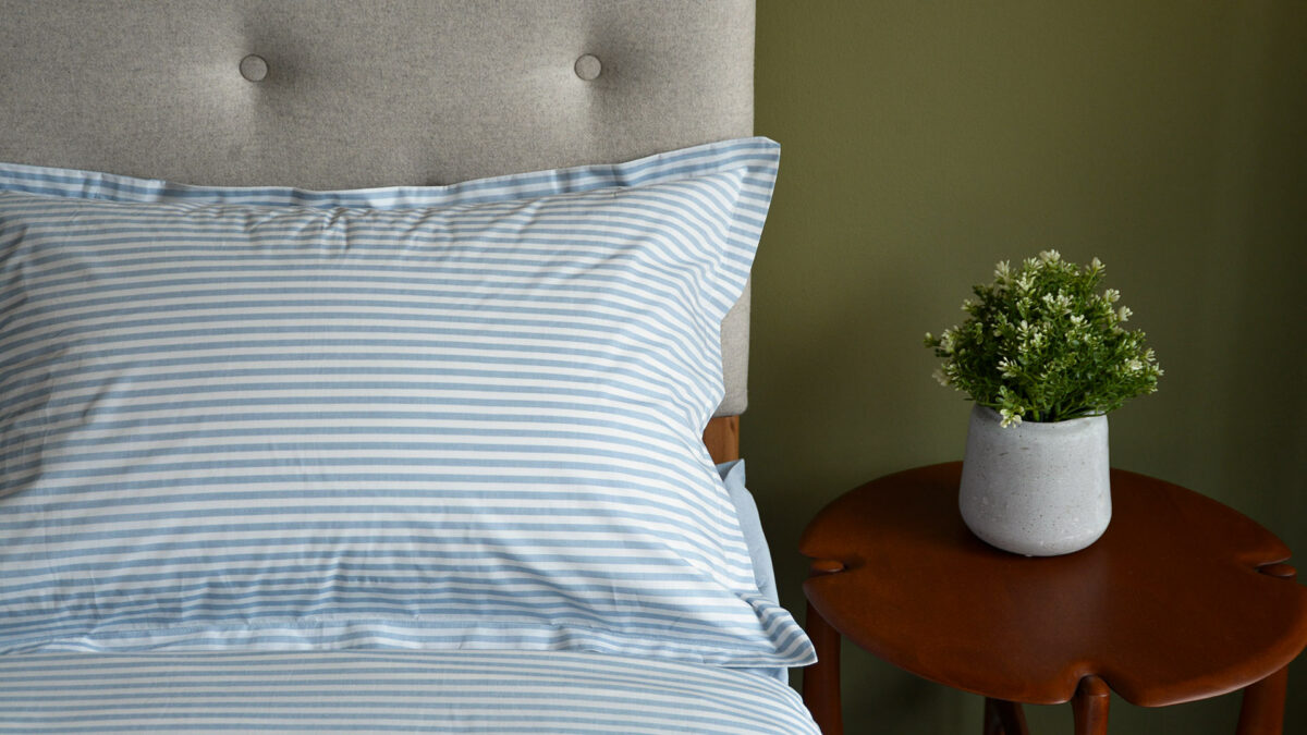 striped cotton bedding pale blue pillow close up with pi table and plant