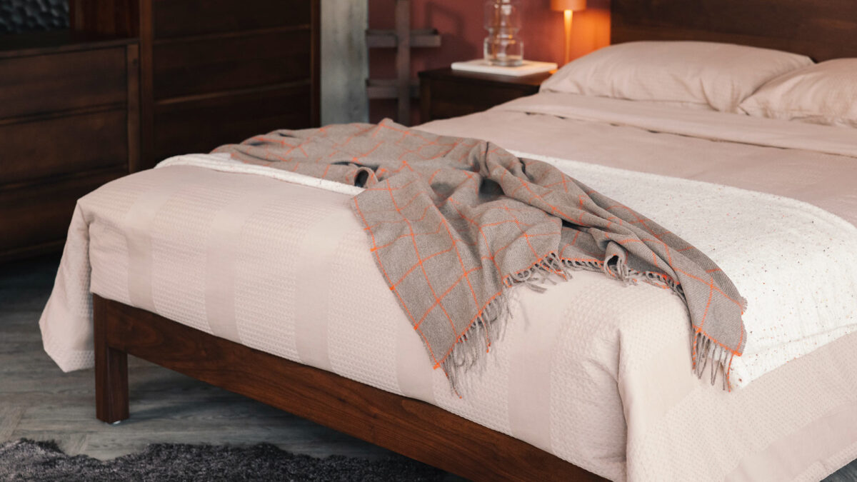 taupe cashmere throw with orange windowpane pattern on waffle stripe bedding