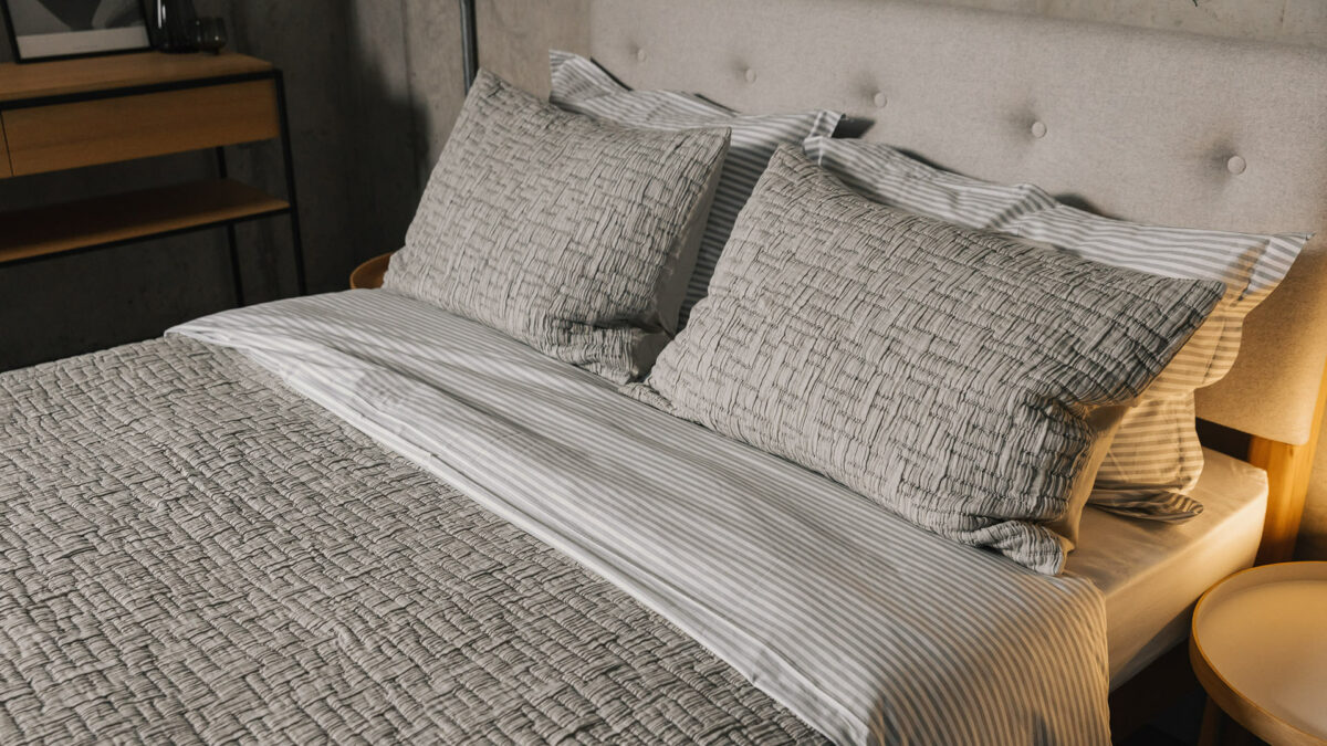 grey textured bedspread with matching pillowcases shown on a bed