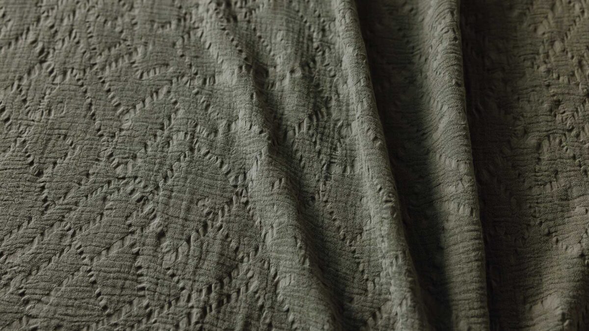 Close up of an olive green throw with textured ribbon pattern.