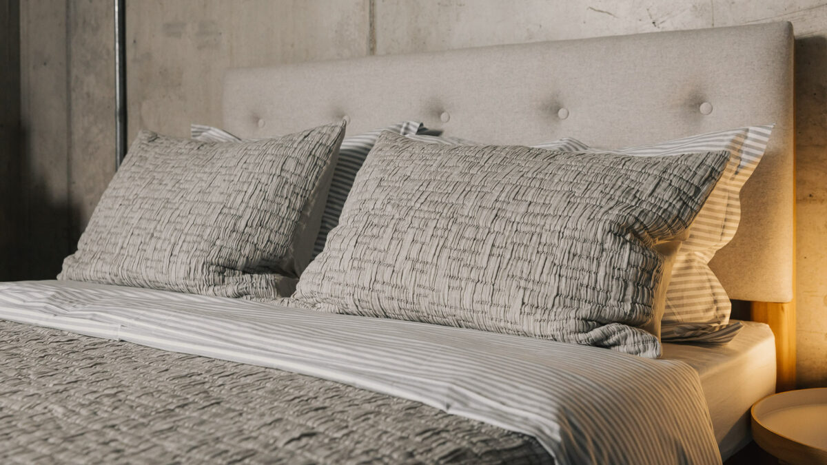 grey textured bedspread with matching pillowcases shown on a bed