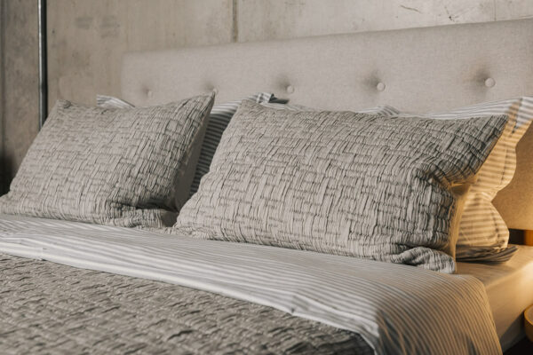 grey textured bedspread with matching pillowcases shown on a bed