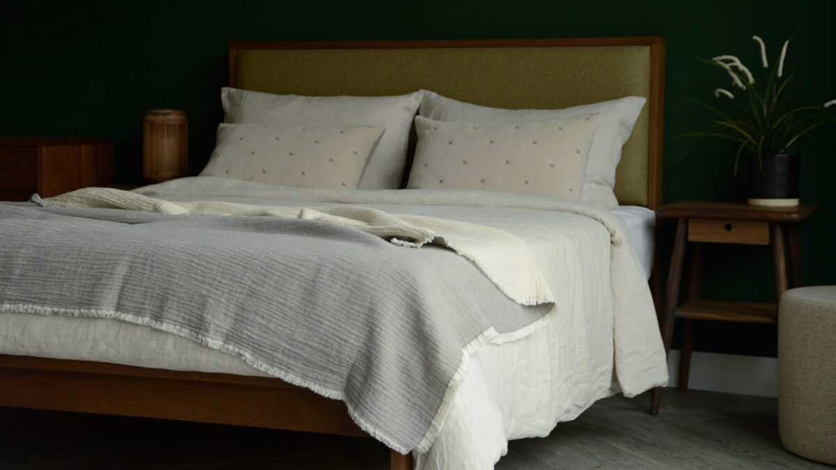 organic cotton reversible throw in pale grey and ivory shown on a kingsize bed