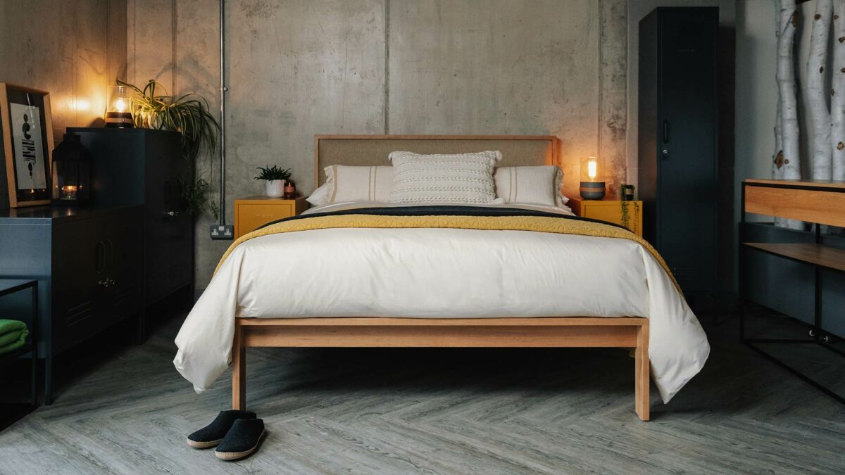 Industrial look bedroom featuring the Shetland taller wooden bed in cherry with wool fabric-covered padded headboard