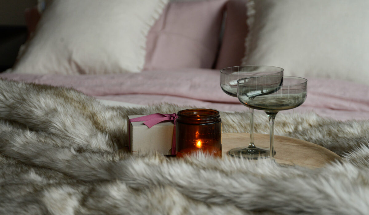 valentines day champagne glasses on bed with candle