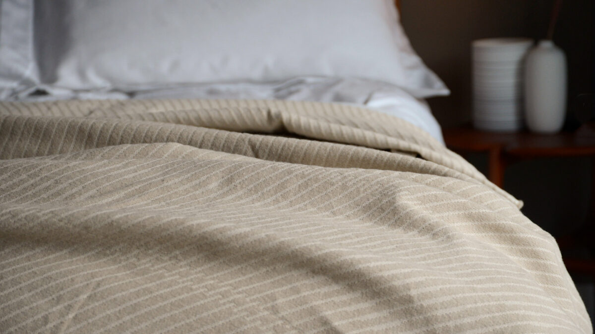 soft cotton striped bedspread in beige shown on a bed