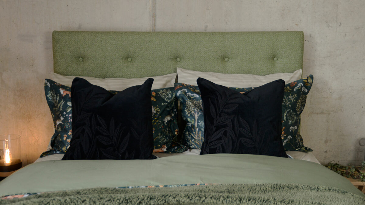 black velvet cushions with black embroidered leaves design shown on a kingsize upholstered bed