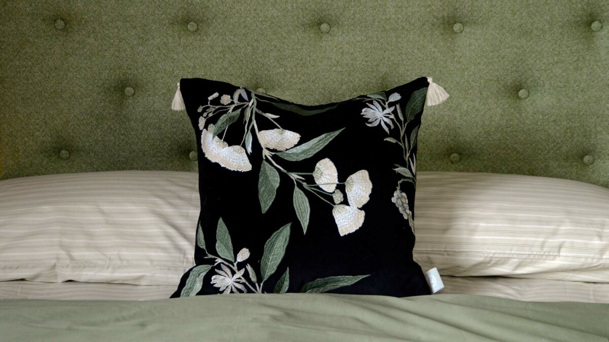 A floral embroidered black velvet cushion with corner tassels