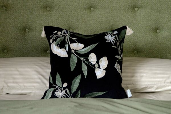 A floral embroidered black velvet cushion with corner tassels