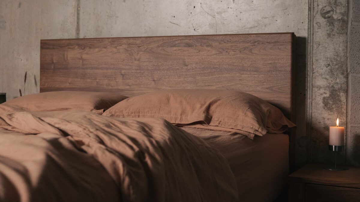 walnut wood Chiswick bed shown with rust coloured muslin look bedding