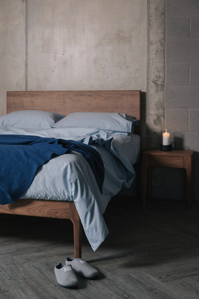 walnut bed and bedside table with blue bedding portrait