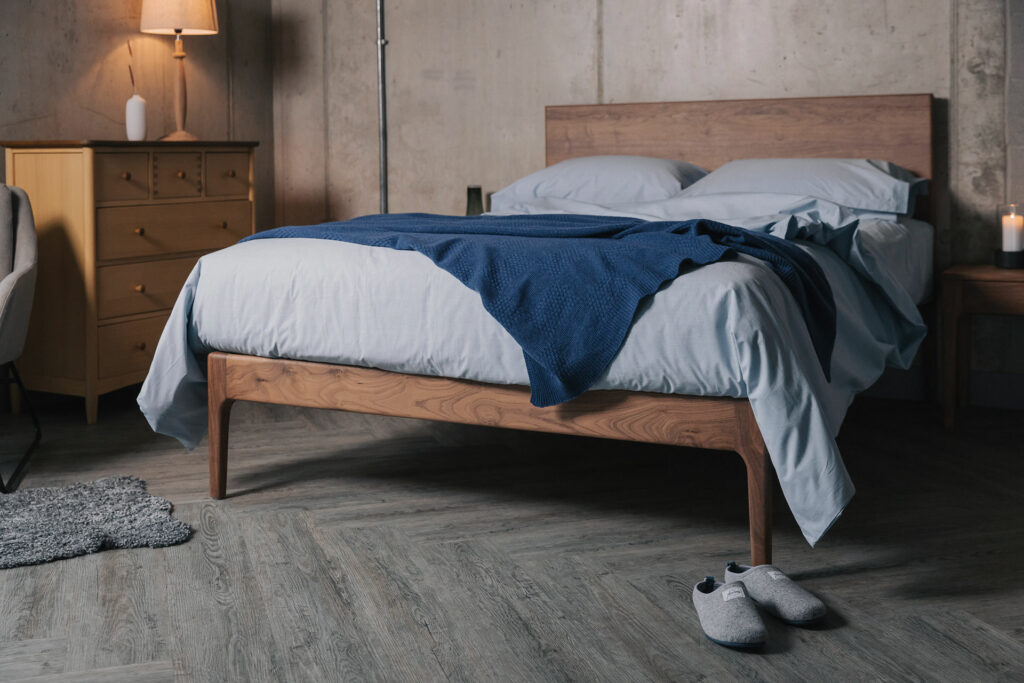 Pale blue Chambray bedding with a luxury knitted cashmere throw shown on a walnut wood bed