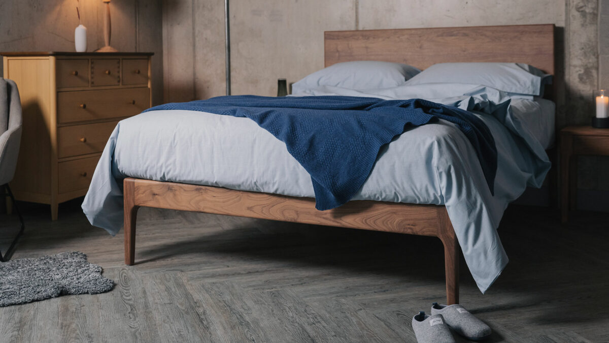 Pale blue Chambray bedding with a luxury knitted cashmere throw shown on a walnut wood bed