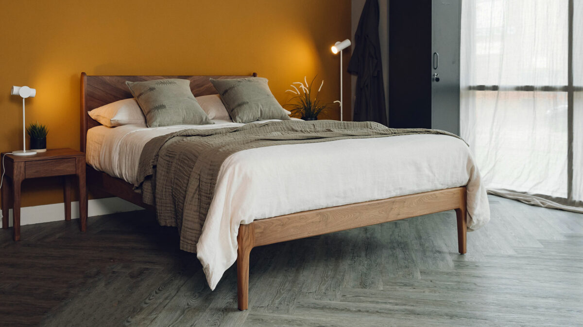 Autumn colours bedroom with yellow ochre walls, a walnut wood bed and olive green cushions