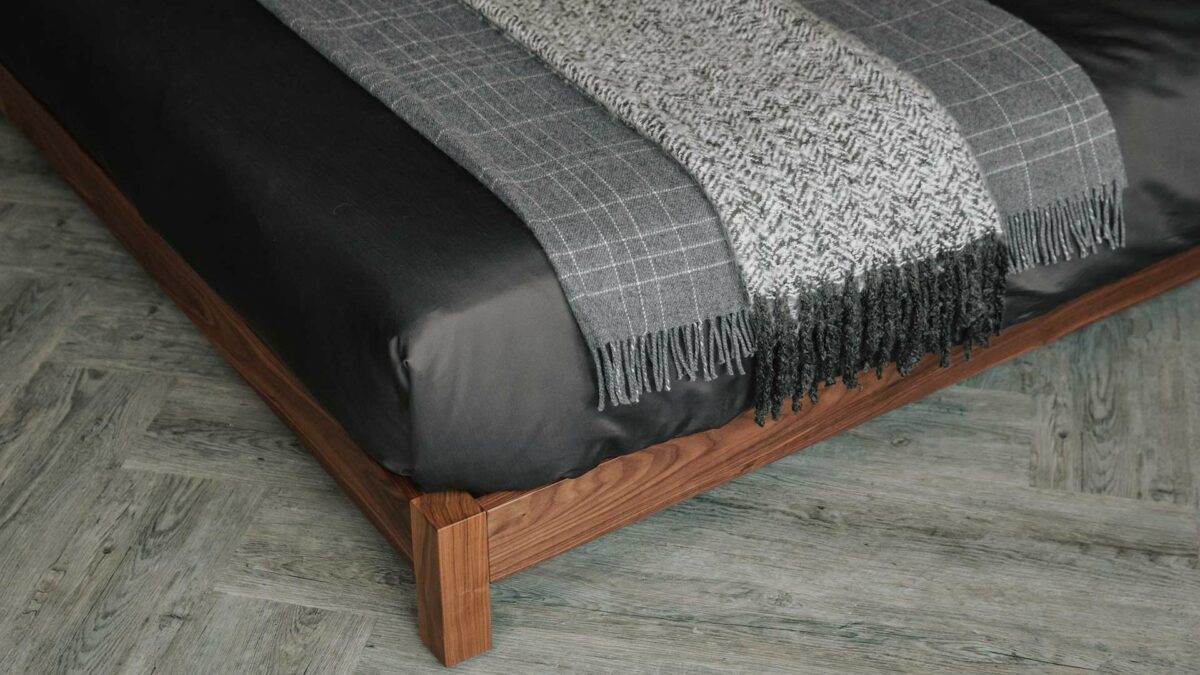 Detail view of Iona low bed foot and side rails with Grey and ivory throws on our luxury bedding