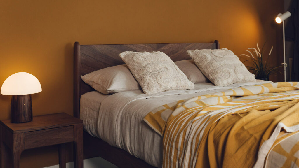 Autumn colours bedroom style with Walnut bed and table, sand coloured linen bedding and an ochre and ivory light bedspread