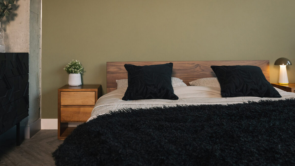 Walnut wood Superking Sonora bed shown with a black faux fur soft curly throw and embroidered black velvet cushions