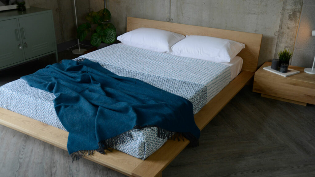 Oregon low platform bed in oak shown with blue and white bedding