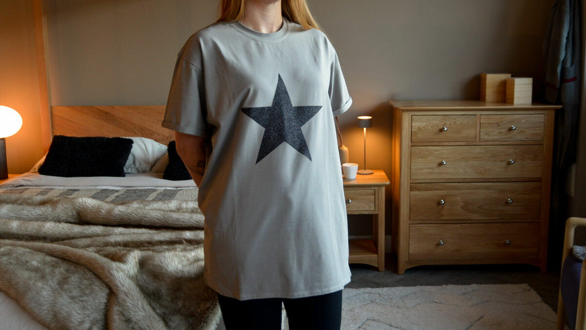 grey T shirt with black glitter star motif shown on a model