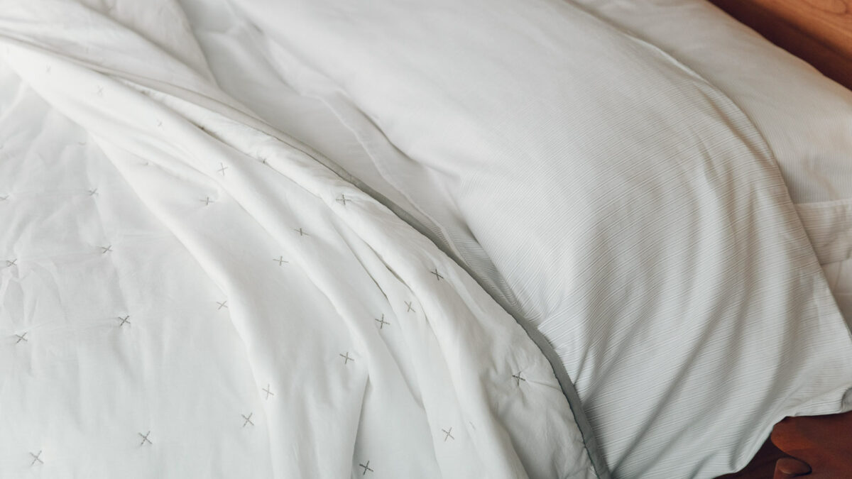 lightly striped grey and white duvet cover set shown with a white quilted bedspread