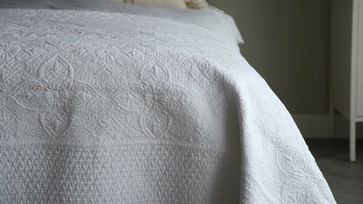 embroidered and quilted white cotton bedspread with contrast stitched border