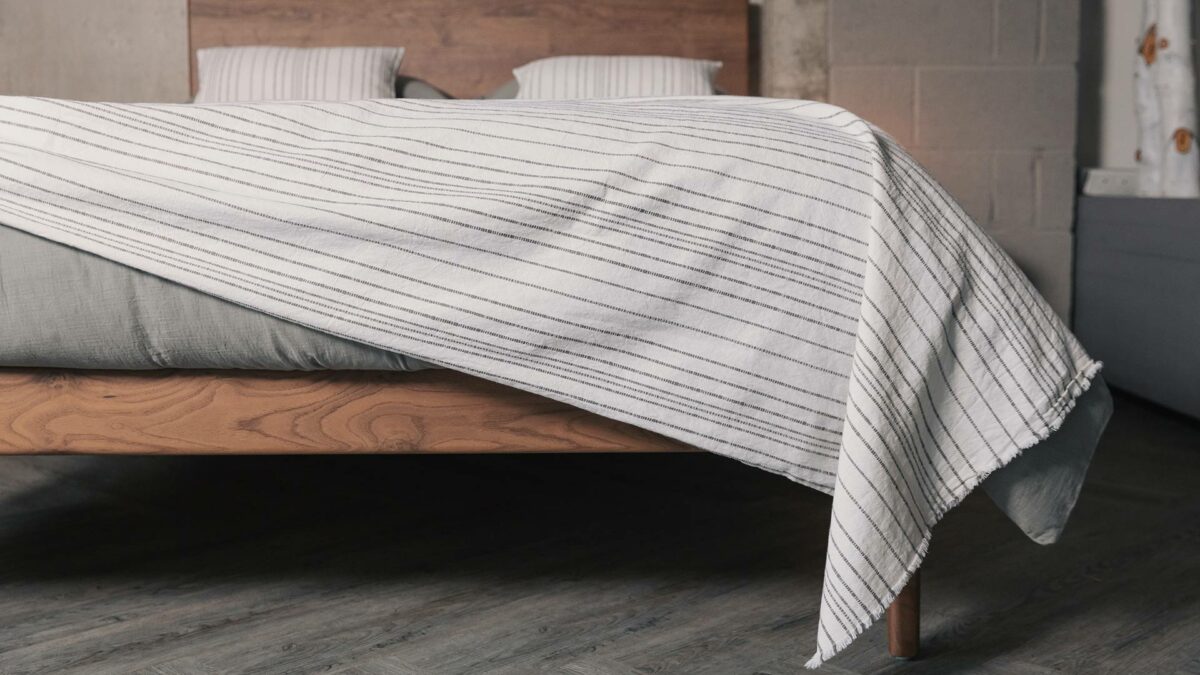 white cotton throw with woven in grey stripes shown on a kingsize bed