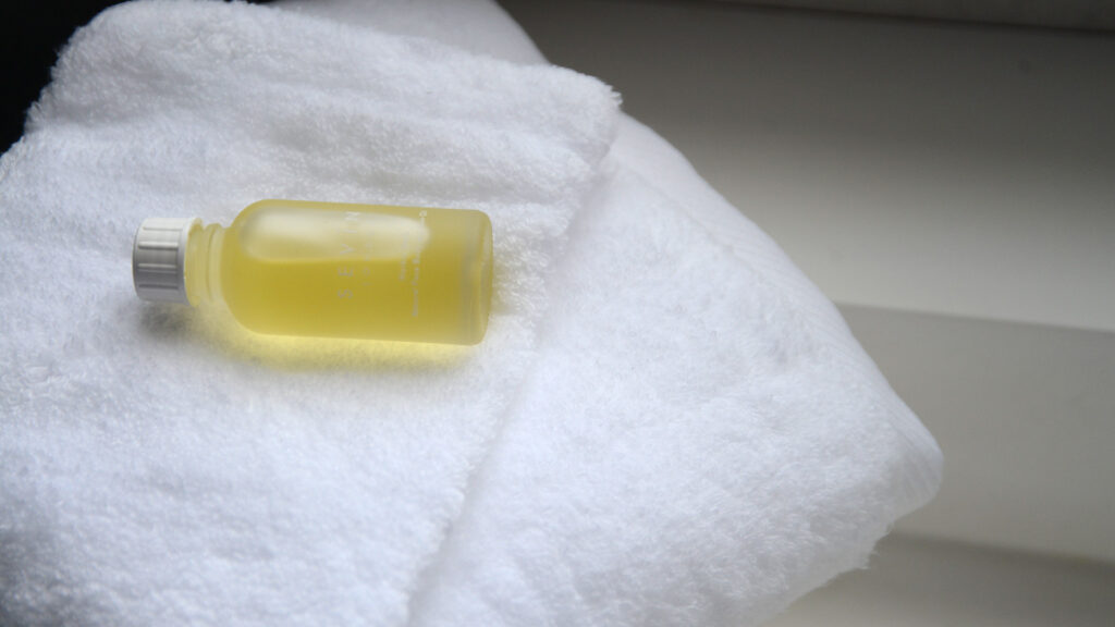 softest white hand towel shown with body oil