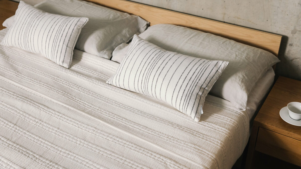 white kantha bedspread with striped cushions