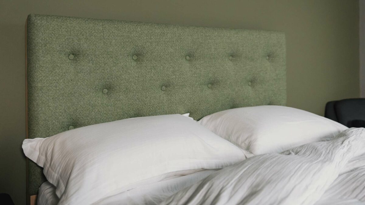 Skye wooden bed tall headboard panel buttoned and upholstered in a green Parquet wool fabric