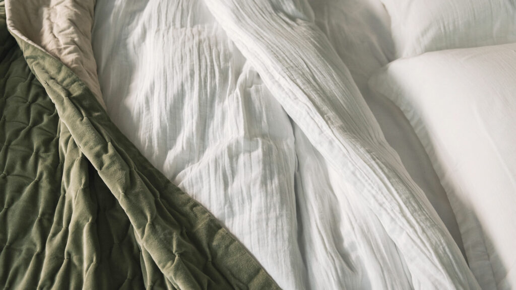 muslin like white cotton bedding shown with olive green velvet throw