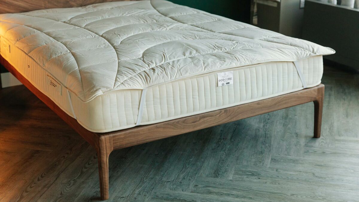 organic wool filled cosy mattress topper shown on a hand made walnut Hoxton bed frame