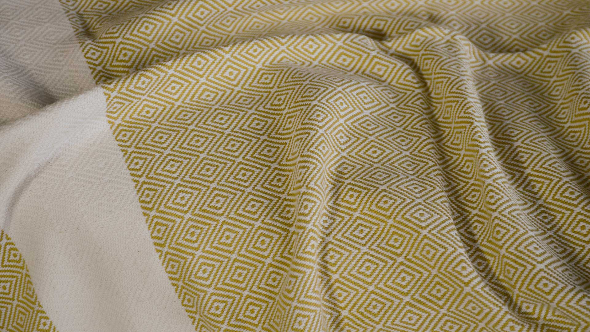 cotton blanket with a woven diamond pattern shown close up and in chartreuse